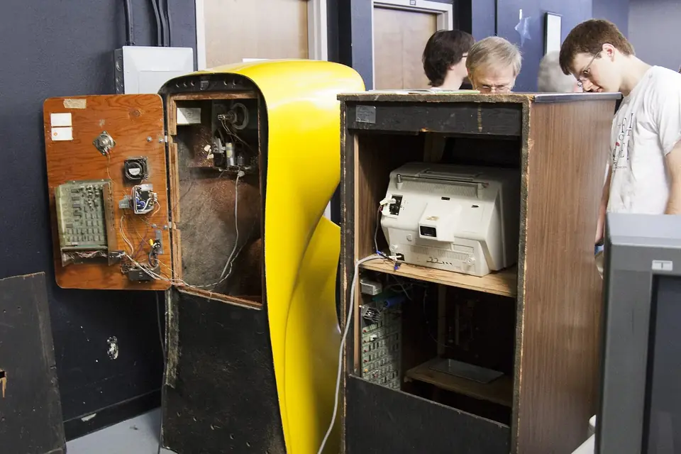 L'arrière ouvert de deux bornes d'arcade anciennes, l'une jaune et arrondie, l'autre en bois, avec leurs circuits visibles