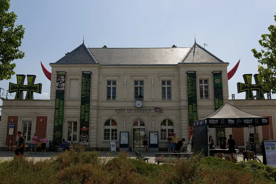 La gare de Clisson, bâtiment de pierre claire à deux niveaux, décorée de grandes croix métalliques et de bannières noires