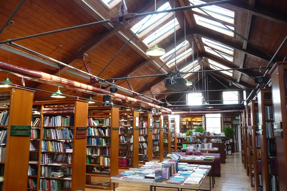 Intérieur d'une librairie ancienne avec de hauts rayonnages de livres en bois et une allée centrale