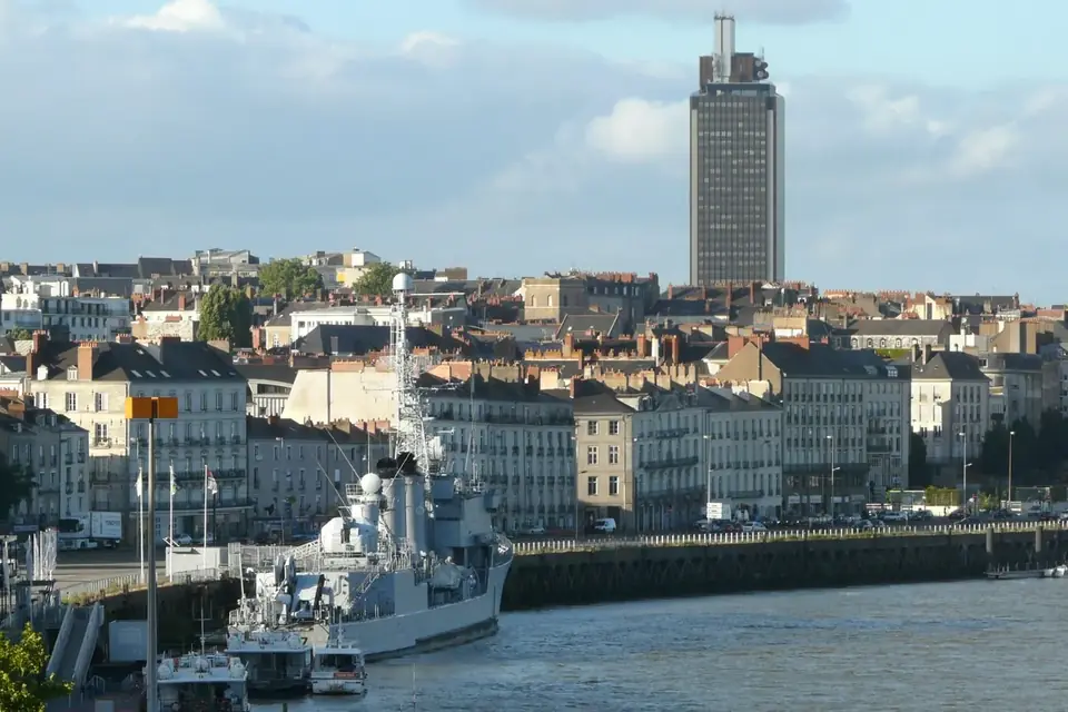 Immeubles des quais de Nantes au bord de la Loire, dominés par la tour Bretagne, avec un ancien navire militaire amarré au quai