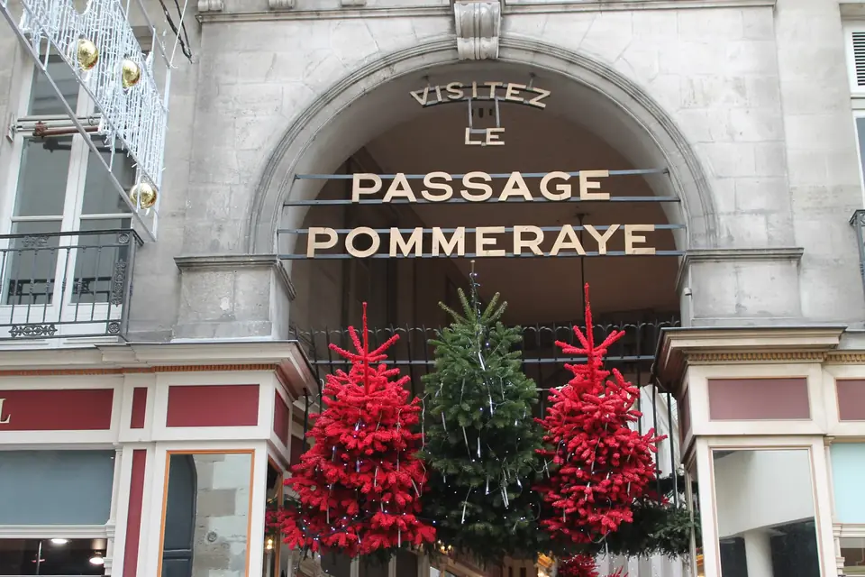 L'entrée du passage Pommeraye surmontée de son enseigne, décorée de sapins rouges et verts pour les fêtes